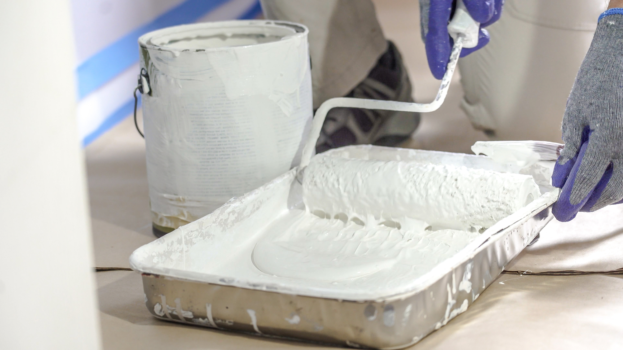 Close Up Shot of White Paint being applied on a Roller. Paint is in the Tray. Room Renovations at Home.